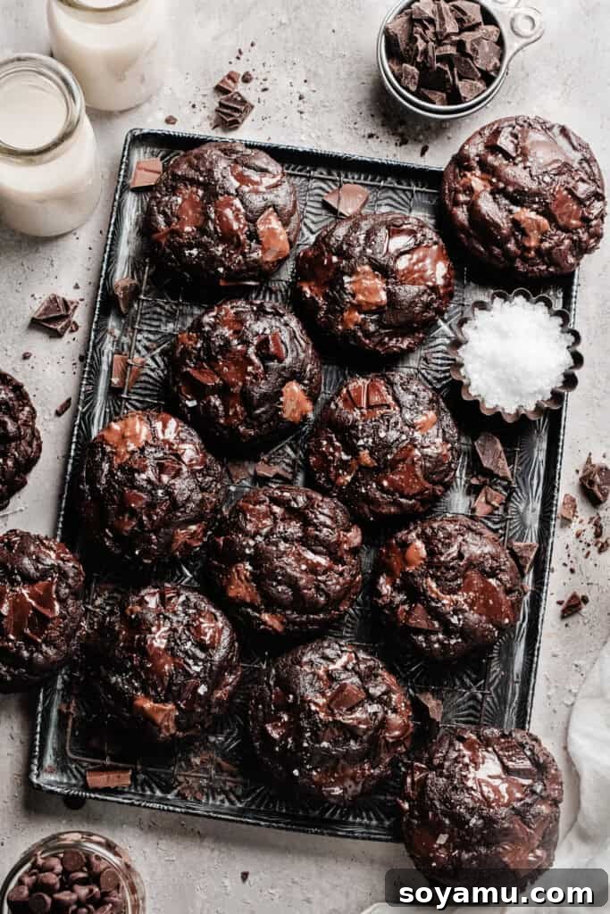 Triple Chocolate Chunk Cookies - World, meet Triple Chocolate Chunk Cookies! Ultra fudgy, with crackly tops - and three kinds of chocolate chunks! We're mixing semi-sweet, milk, and dark chocolate to make the richest possible chocolate cookie. Sprinkle some flaky sea salt over those melted pools of chocolate and dive in to dessert heaven! #chocolatecookies #cookierecipes #dessertrecipes #cookies #chocolaterecipes #chocolatedesserts #bluebowlrecipes | bluebowlrecipes.com Triple chocolate cookies arranged artfully on a vintage serving tray, highlighting their appealing dark color and inviting texture.