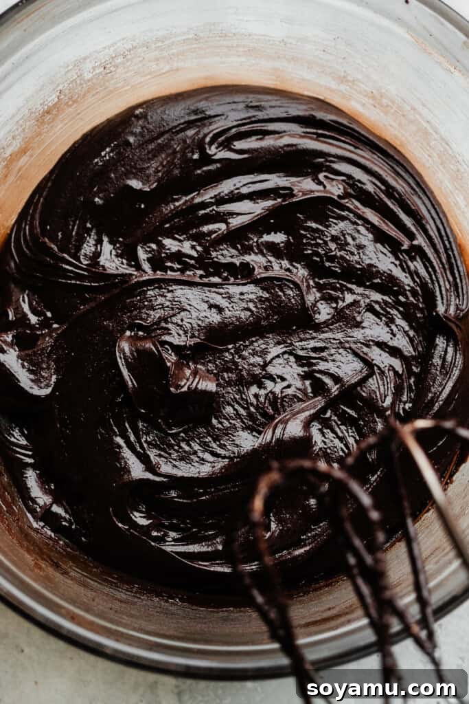 Ultimate Fudgy Triple Chocolate Cookies 3 A close-up view of thick, rich chocolate cookie batter in a bowl, showcasing its dense texture before adding chocolate chunks.