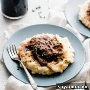 Beer Braised Short Ribs with Cheddar Mashed Potatoes Short ribs on a bed of cheddar mashed potatoes, on plates.