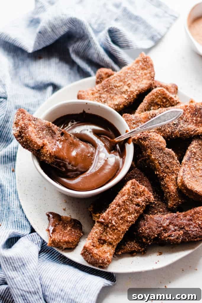 A beautiful platter of Churro French Toast Sticks with chocolate sauce Finished french toast sticks on plate with chocolate sauce