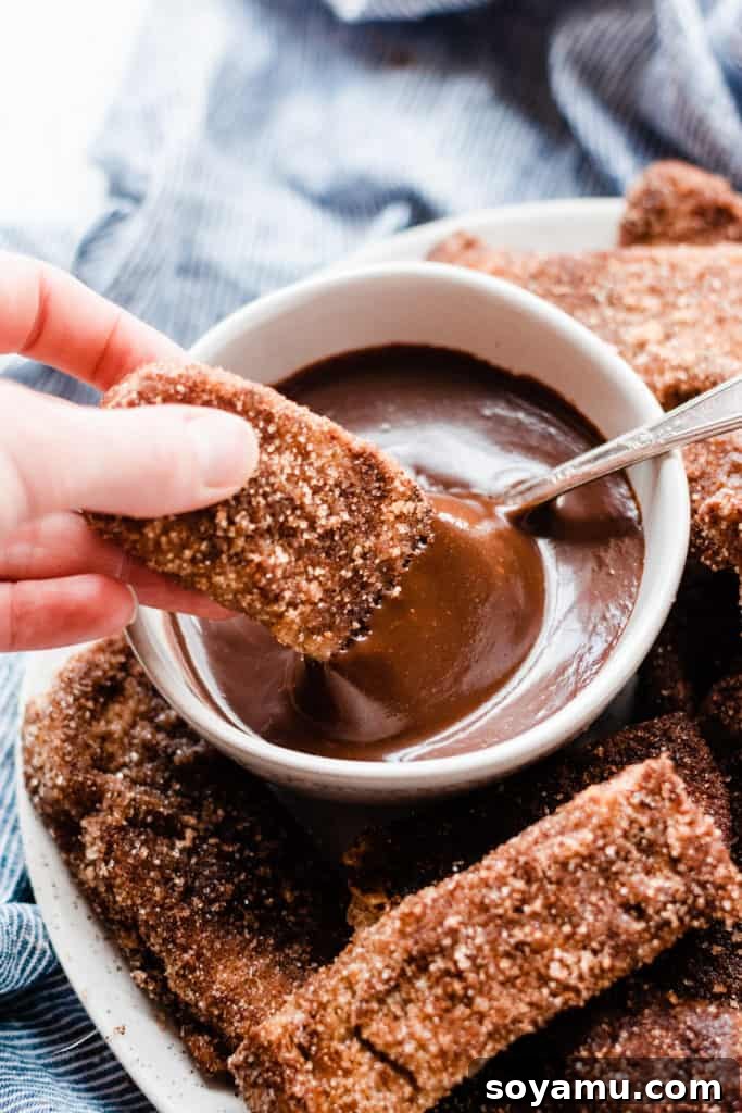 A single Churro French Toast Stick being dipped into luscious chocolate sauce Finished french toast stick dipped in chocolate sauce