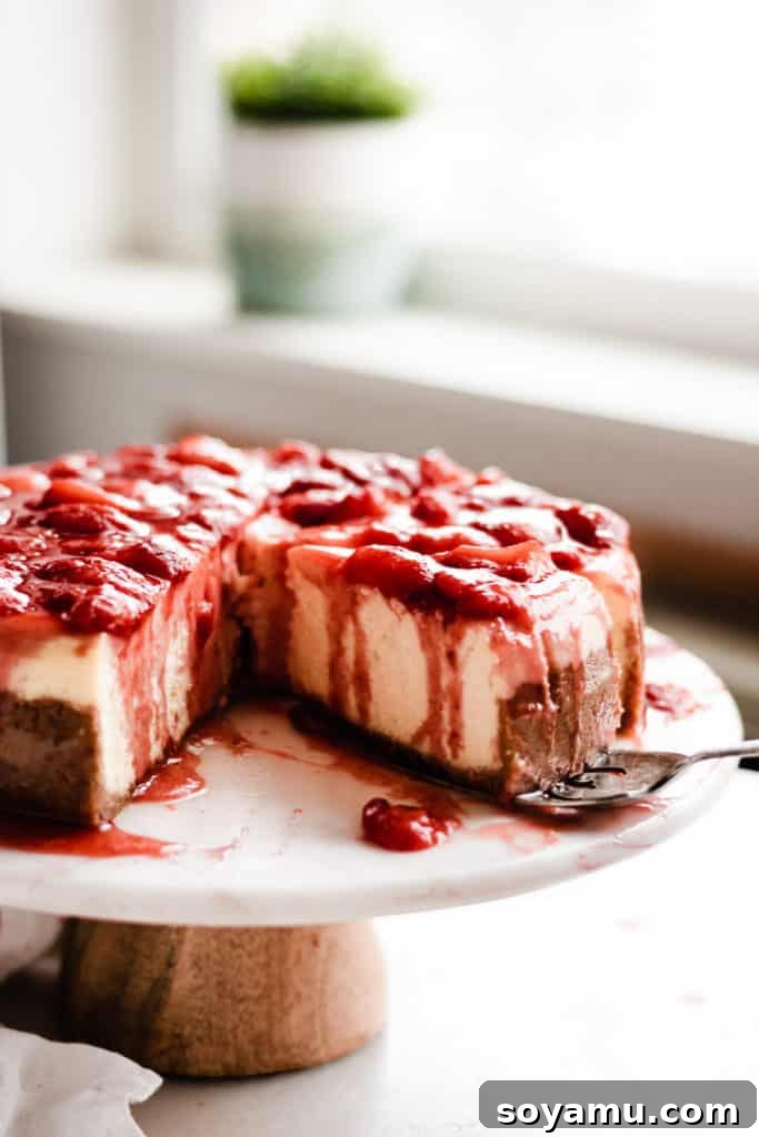 Strawberry Cheesecake Display A stunning full shot of the sliced strawberry cheesecake on a pristine cake stand, beautifully presented and ready to be devoured.