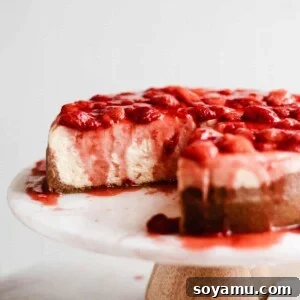 Strawberry Cheesecake Perfection 3 Sliced classic cheesecake on a cake stand with a generous topping of homemade strawberry sauce.