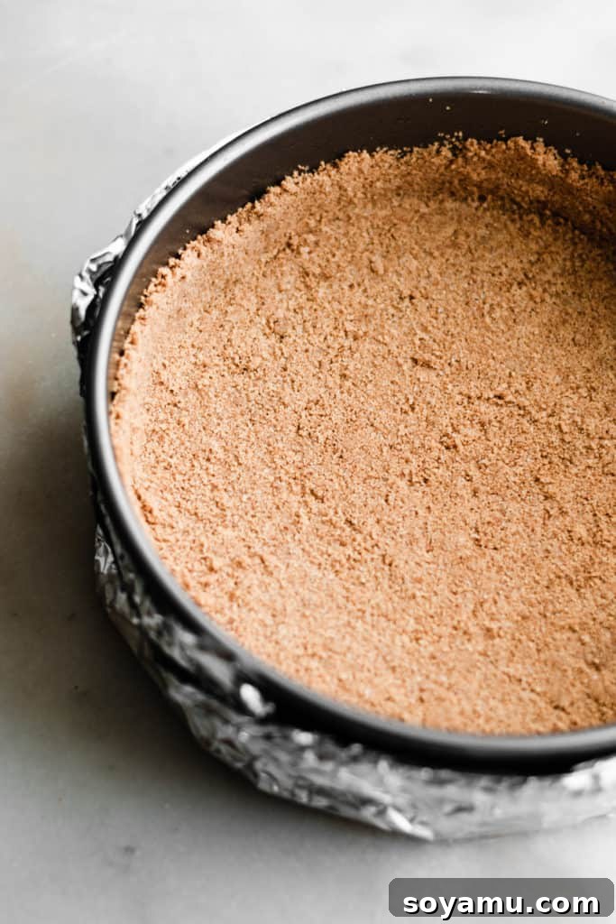 Graham Cracker Crust in a Springform Pan The perfectly pressed graham cracker crust lining the bottom and sides of a springform pan, providing a sturdy base for the cheesecake filling.