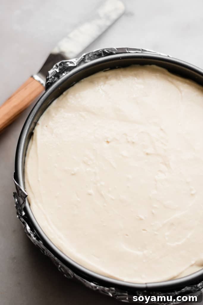 Cheesecake Filling Ready for Baking Unbaked cheesecake filling, smooth and evenly spread within the graham cracker crust in a springform pan, perfectly ready for the oven.
