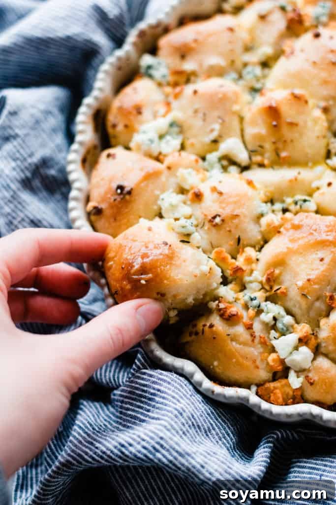 Close-up view of golden brown cheesy bread bites inside a round baking pan, showcasing their fluffy texture.