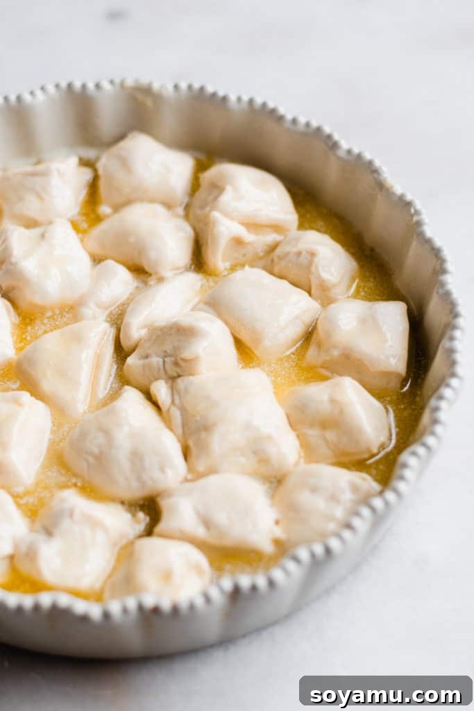 Close-up of fluffy bread dough pieces glistening with melted butter in a baking dish.