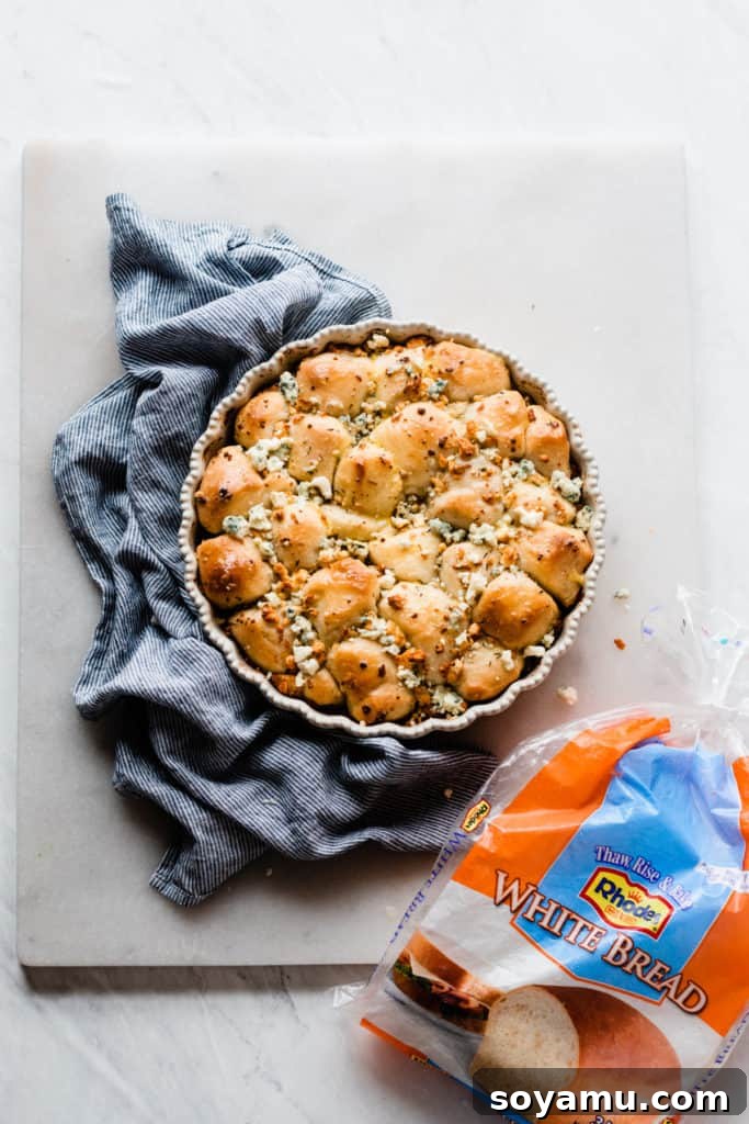 Finished cheesy baked bread bites in a round pan, bubbling with melted cheese and golden crusts.