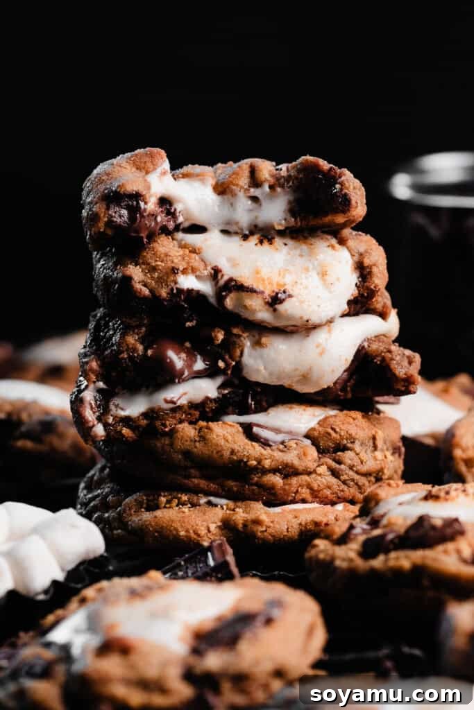 Marshmallow Stuffed S'mores Cookies 3 A tall stack of s'mores cookie halves, with gooey marshmallow centers oozing out.