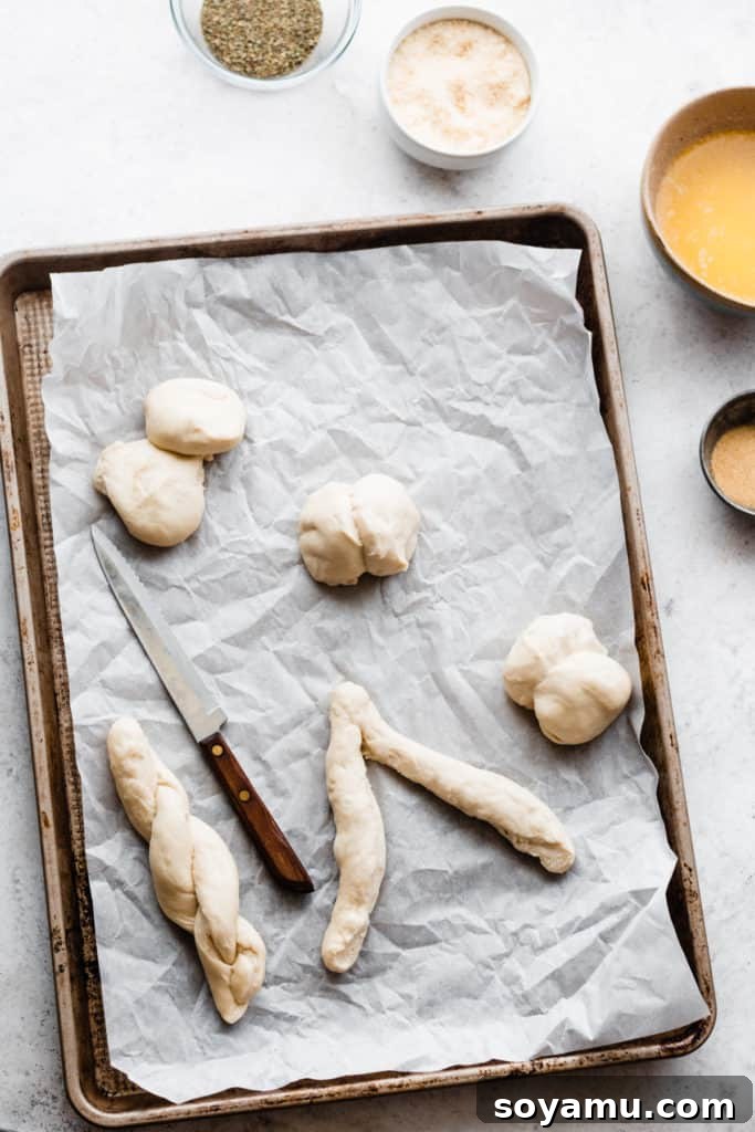 A sheet pan showcasing balls of thawed dough being expertly twisted into elegant breadstick shapes before baking.