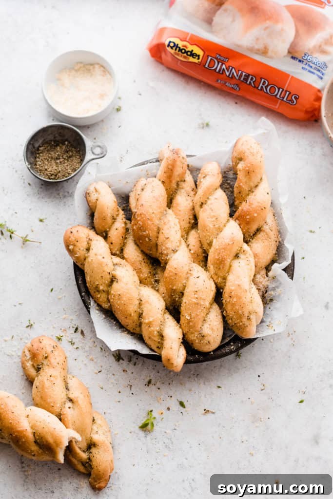 A plate of parmesan and herb sprinkled twisted breadsticks, freshly baked and served, with the Rhodes dinner roll bag visible in the background.