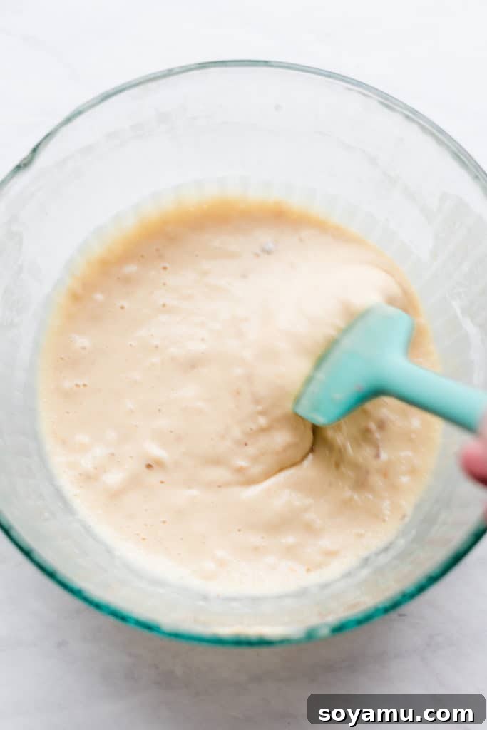 Smooth buttermilk waffle batter in a clear glass bowl, showcasing its perfect consistency