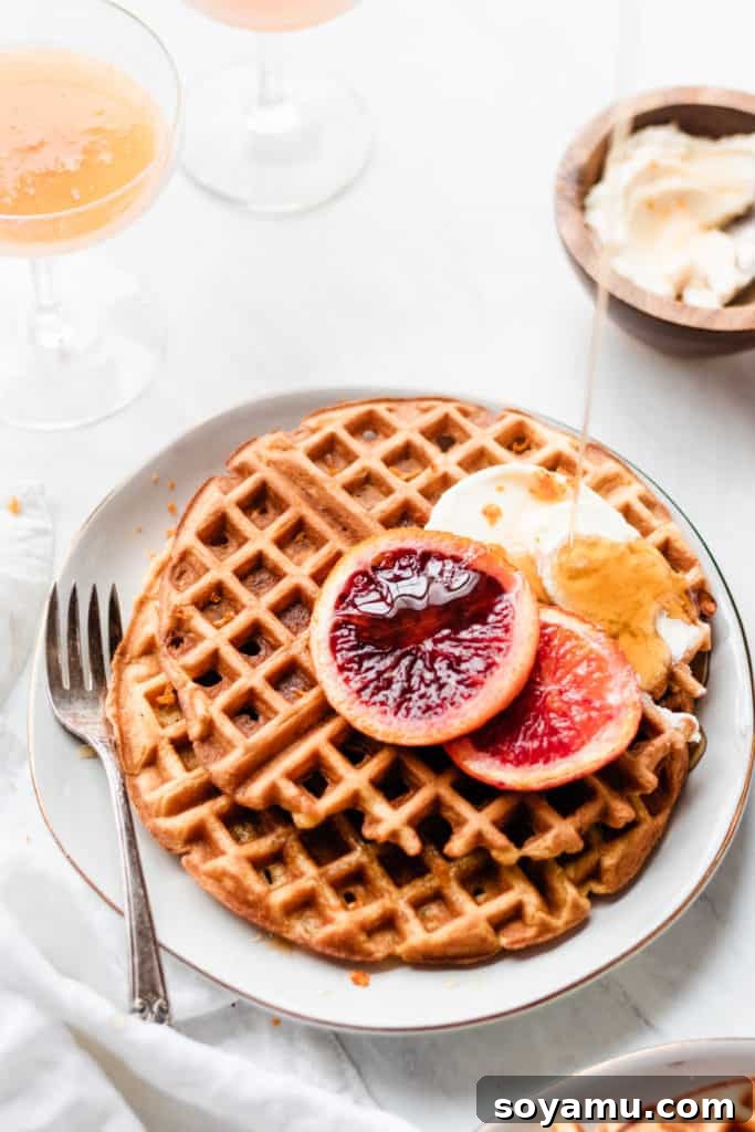 A beautifully plated dish featuring sliced buttermilk waffles, roasted blood orange segments, and a dollop of honey mascarpone