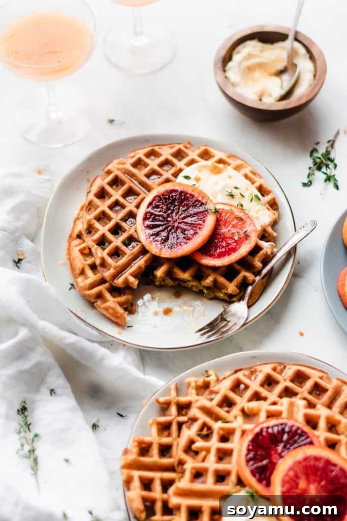 Closeup of freshly sliced buttermilk waffles adorned with roasted blood orange slices on a white plate