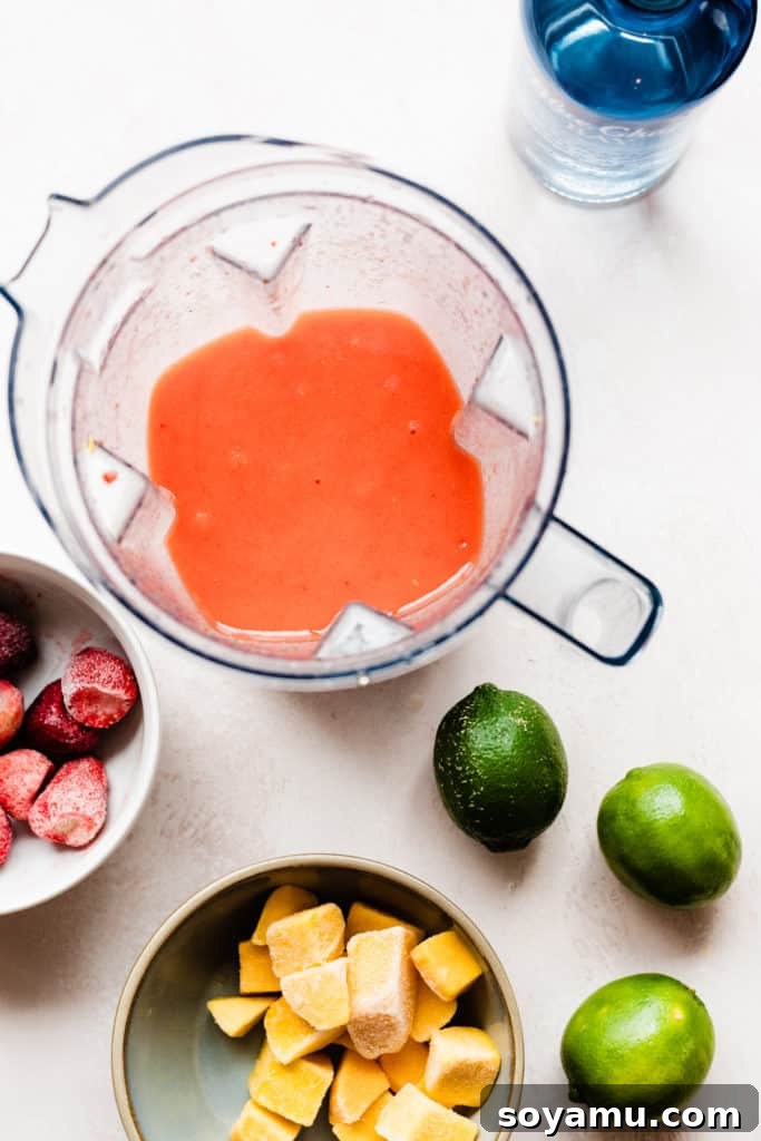 The pinky orange cocktail mixture blended up in the blender, with fruit scattered around