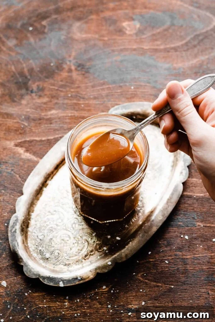 Flaky Caramel Apple Pockets 4 A spoon dipping into a jar of caramel sauce.