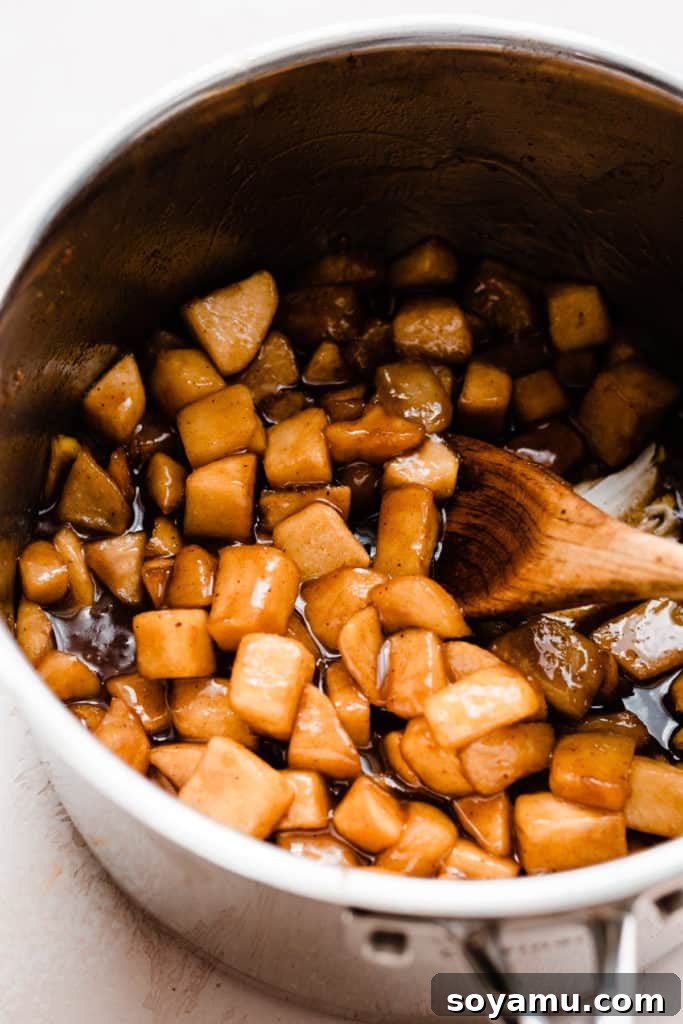 Flaky Caramel Apple Pockets 5 Cooked, golden apple filling in a pot, with a wooden spoon stirring the filling
