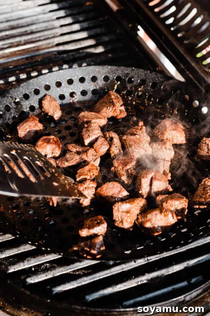 Zesty Lemon Grilled Lamb Power Bowls 3 Chunks of marinated lamb meat sizzling and cooking on a hot grill pan, with subtle char marks indicating the grilling process