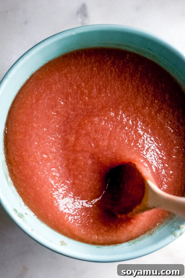 Smooth, naturally pink applesauce in a vibrant blue bowl, ready to be served.