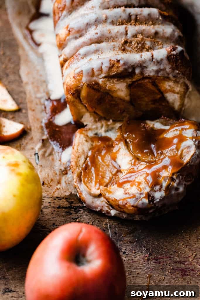 Gooey Caramel Apple Monkey Bread 7 A close-up view of the Caramel Apple Pull Apart Bread, with a few pieces gently pulled away from the loaf, revealing the soft, layered interior and generous drizzles of salted caramel sauce.