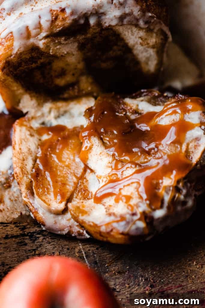 Gooey Caramel Apple Monkey Bread 8 An extremely close-up shot focusing on two delectable pieces of Caramel Apple Pull Apart Bread, liberally drizzled with rich salted caramel sauce, highlighting the moist texture and inviting sweetness.