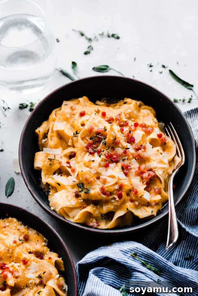 Velvet Butternut Pasta with Savory Pancetta 8 A close-up view of a beautifully presented bowl of creamy butternut squash pasta, generously topped with crispy pancetta, a sprinkle of fresh Parmesan cheese, and a fork ready to scoop, embodying autumnal comfort.