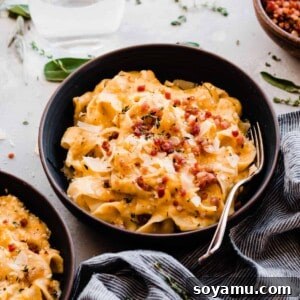 A close-up shot of a bowl filled with creamy butternut squash pasta and crispy pancetta, garnished with fresh herbs, showcasing the rich texture and vibrant colors.