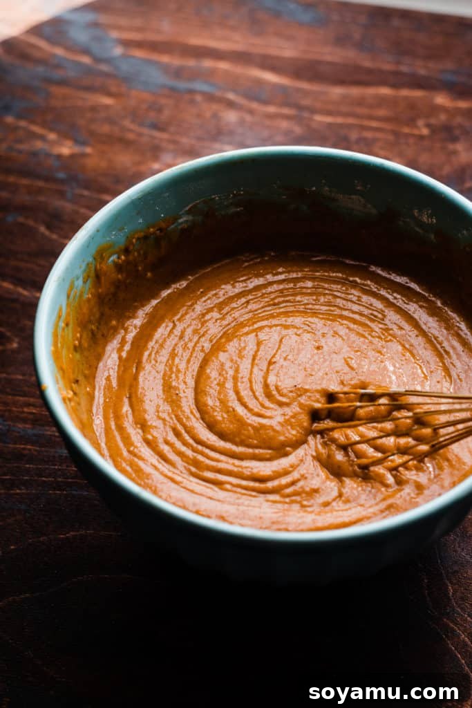 Autumn Pumpkin Delights with Brown Butter Cream Cheese 5 A bowl of creamy batter being whisked, on a wooden surface