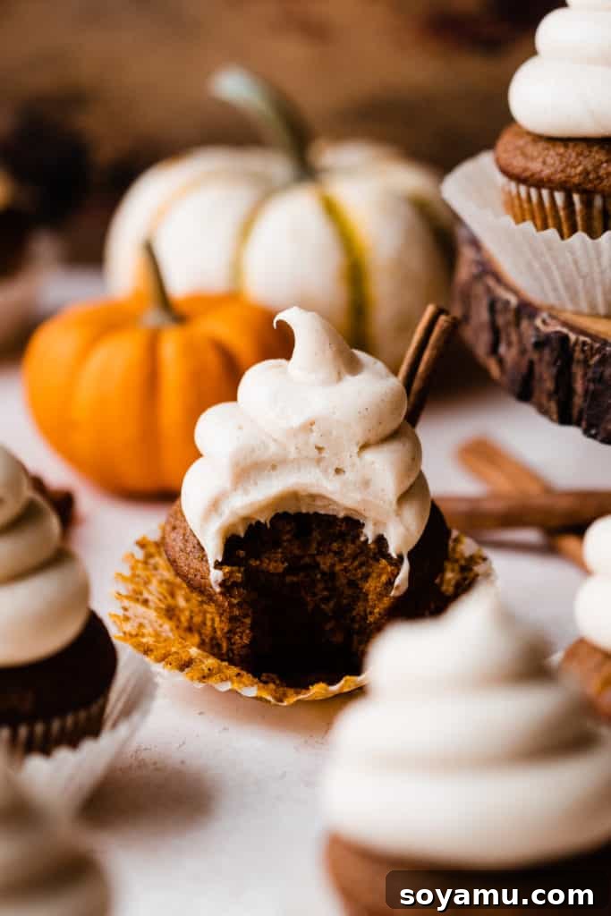Autumn Pumpkin Delights with Brown Butter Cream Cheese 9 A pumpkin cupcake with a bite taken out, with mini pumpkins and cinnamon sticks in the background
