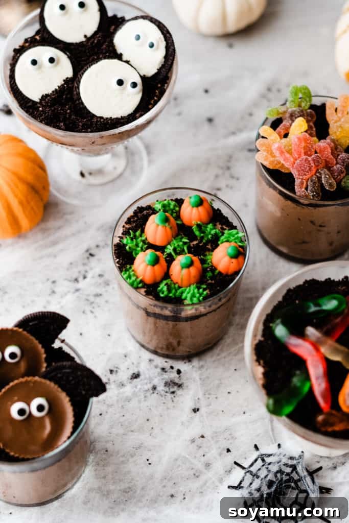 A dirt cup topped with green frosting grass and candy pumpkins