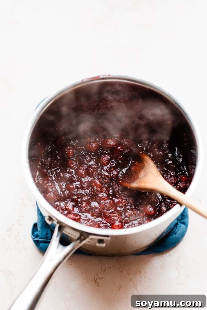 Spiced Rum Cranberry and Gouda Puff Pastry Bites 5 A pot of steaming homemade cranberry sauce, with cranberries visibly broken down, simmering gently on the stovetop, emanating a warm, inviting aroma.