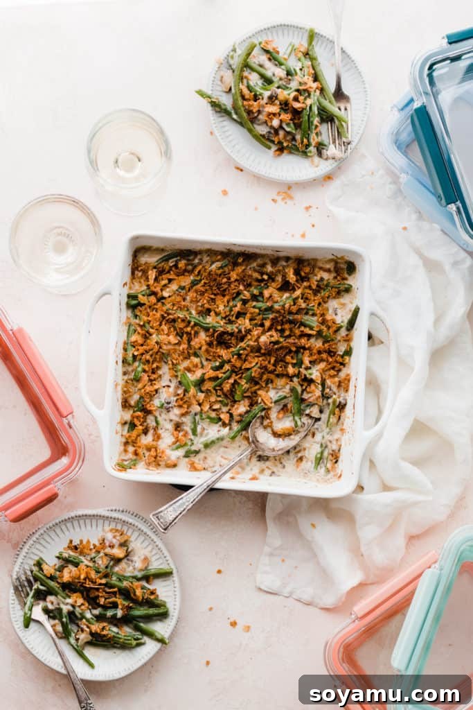 The Ultimate Homemade Green Bean Casserole 3 A festive spread featuring a dish of green bean casserole, elegant wine glasses, plates of the casserole, and a selection of practical Ello meal prep containers, perfect for holiday leftovers.