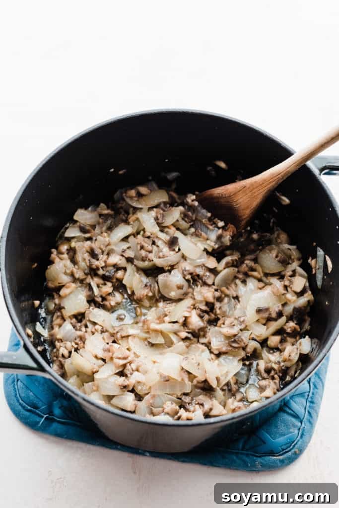 The Ultimate Homemade Green Bean Casserole 4 A pot on the stove filled with perfectly sautéed onions and mushrooms, forming the aromatic base for the green bean casserole sauce.