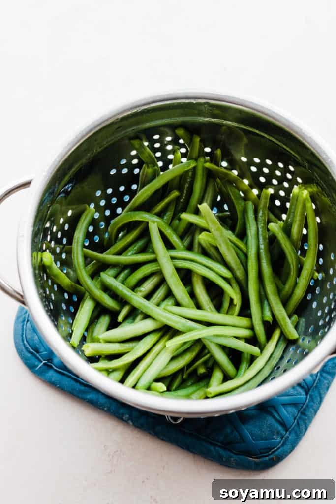 The Ultimate Homemade Green Bean Casserole 6 A colander brimming with vibrant, freshly rinsed green beans, prepared for blanching and destined for the casserole.