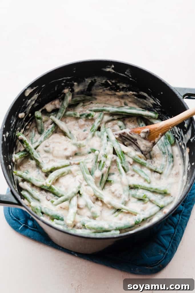 The Ultimate Homemade Green Bean Casserole 7 A large pot containing the combined green bean and creamy mushroom sauce mixture, perfectly blended and ready for transfer to a baking dish.