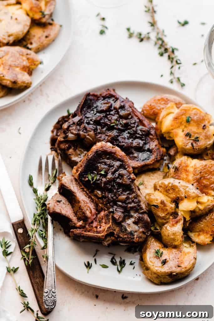 Tender Lamb Chops with Shallot-Thyme Pan Sauce and Creamy Garlic Smashed Potatoes 2 A plate of perfectly cooked lamb chops, drizzled with a savory pan sauce, served next to golden-brown garlic smashed potatoes and garnished with fresh thyme.