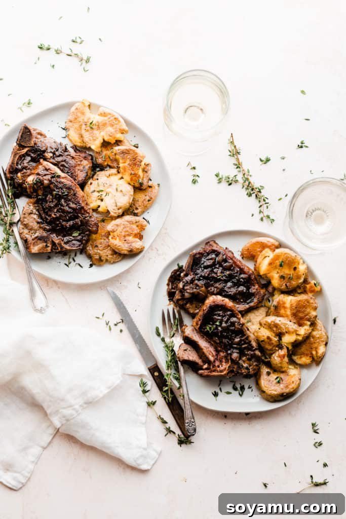 Tender Lamb Chops with Shallot-Thyme Pan Sauce and Creamy Garlic Smashed Potatoes 3 Two elegantly plated dishes of lamb chops and golden smashed potatoes, set with wine glasses and a linen napkin, signifying a special meal.