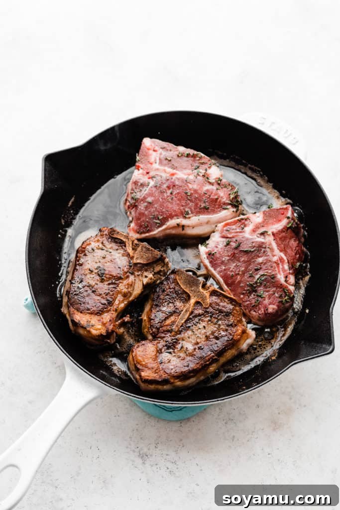 Tender Lamb Chops with Shallot-Thyme Pan Sauce and Creamy Garlic Smashed Potatoes 6 A large skillet containing four sizzling lamb chops, beautifully browning on the stovetop.