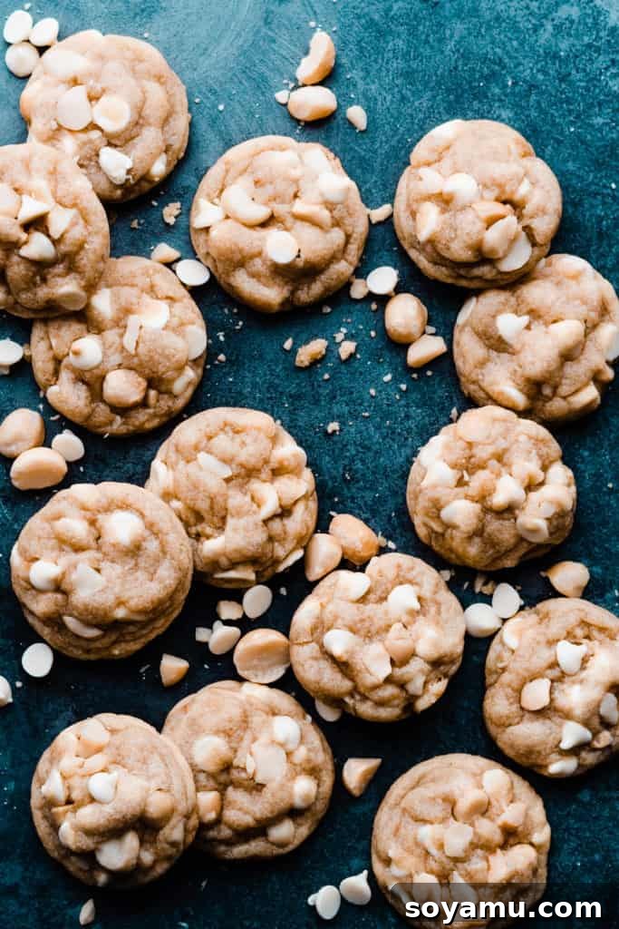 A cluster of freshly baked white chocolate and macadamia nut cookies, arranged artfully on a blue surface, inviting viewers to appreciate their texture and deliciousness.