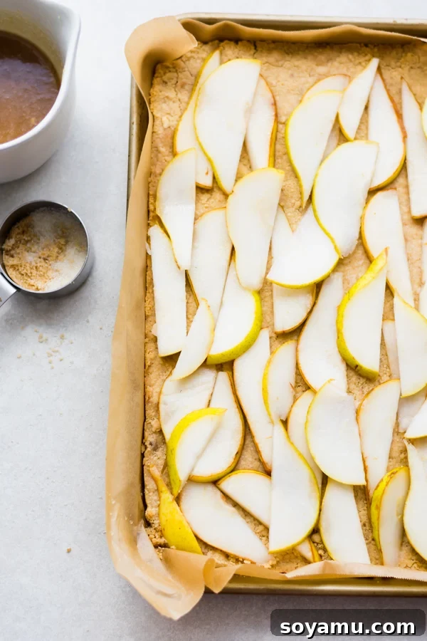 Incredibly Delicious Pear Crumble Bars - Fresh pear slices on a crumble crust base. Thinly sliced fresh pears arranged on a baked crumble crust in a baking pan.