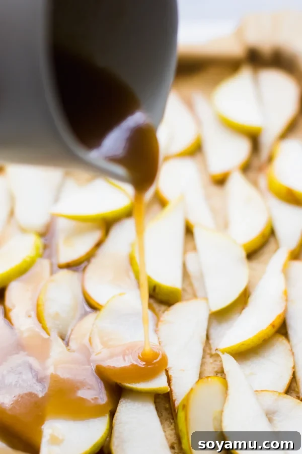 Incredibly Delicious Pear Crumble Bars - Caramel sauce being poured over pear slices. Close-up of golden brown caramel sauce being drizzled over thinly sliced pears.