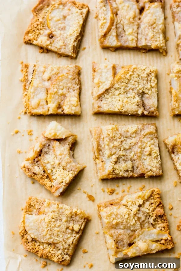 Incredibly Delicious Pear Crumble Bars - Baked pear crumble bars in a pan. Freshly baked pear crumble bars, golden brown and glistening, cooling in the pan.