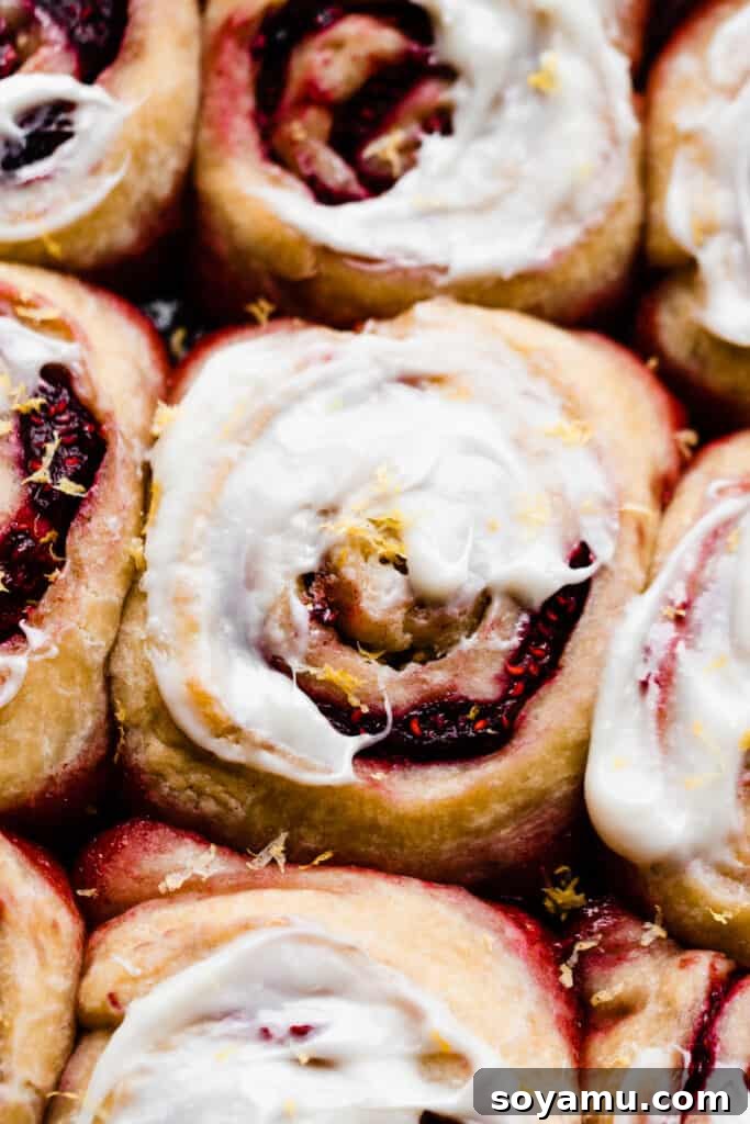 Tangy Raspberry Lemon Morning Buns with Cream Cheese Glaze 11 A close-up photograph showcasing the intricate swirls of a sweet roll, topped with rich cream cheese icing.