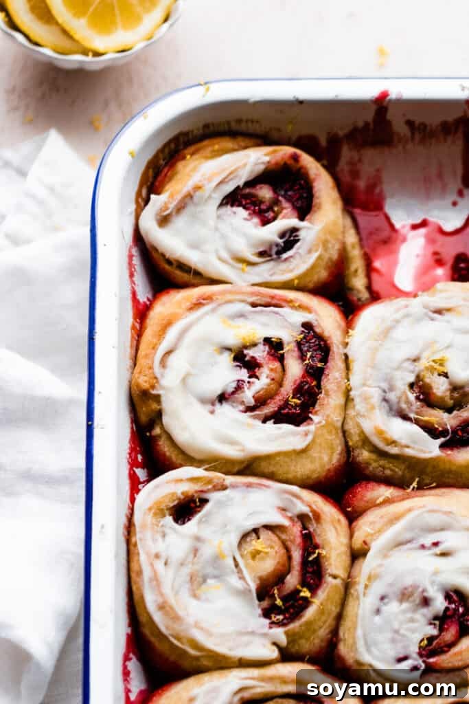 Tangy Raspberry Lemon Morning Buns with Cream Cheese Glaze 3 A close-up of a baking pan filled with Raspberry Lemon Sweet Rolls, with a few already enjoyed.