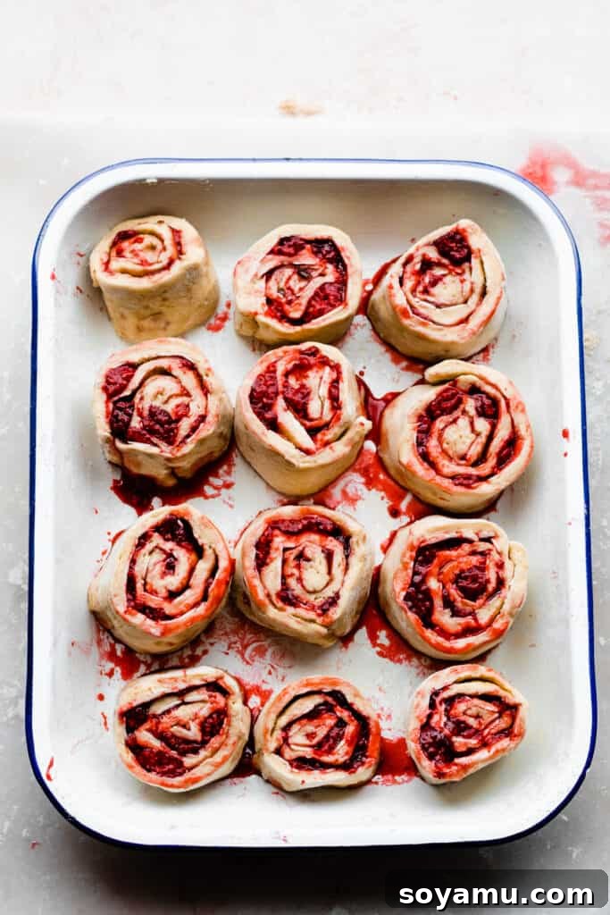 Tangy Raspberry Lemon Morning Buns with Cream Cheese Glaze 7 A pan of neatly arranged sweet rolls, brimming with raspberry filling, just before their final rise.