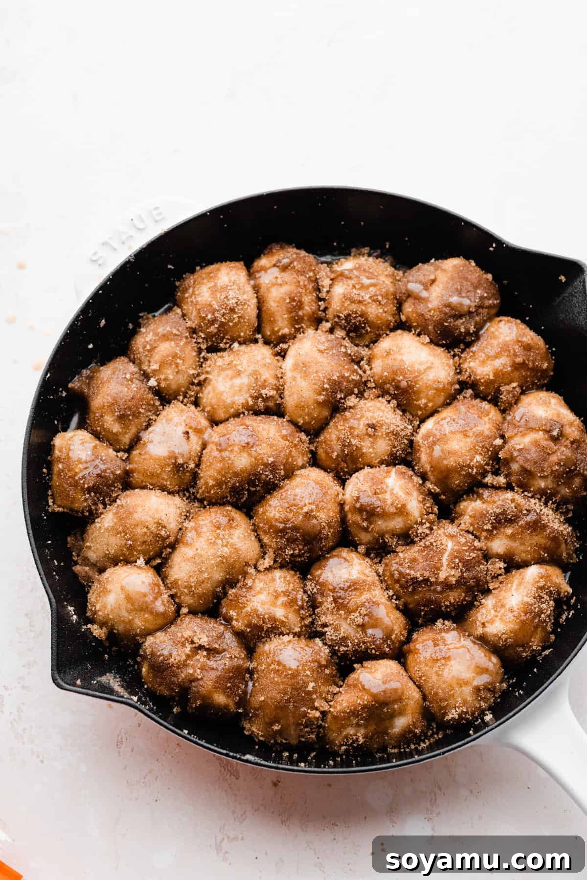 Gooey Skillet Cinnamon Roll Goodness 4 A skillet filled with dough pieces, beautifully coated in melted butter and cinnamon sugar, arranged snugly before baking.