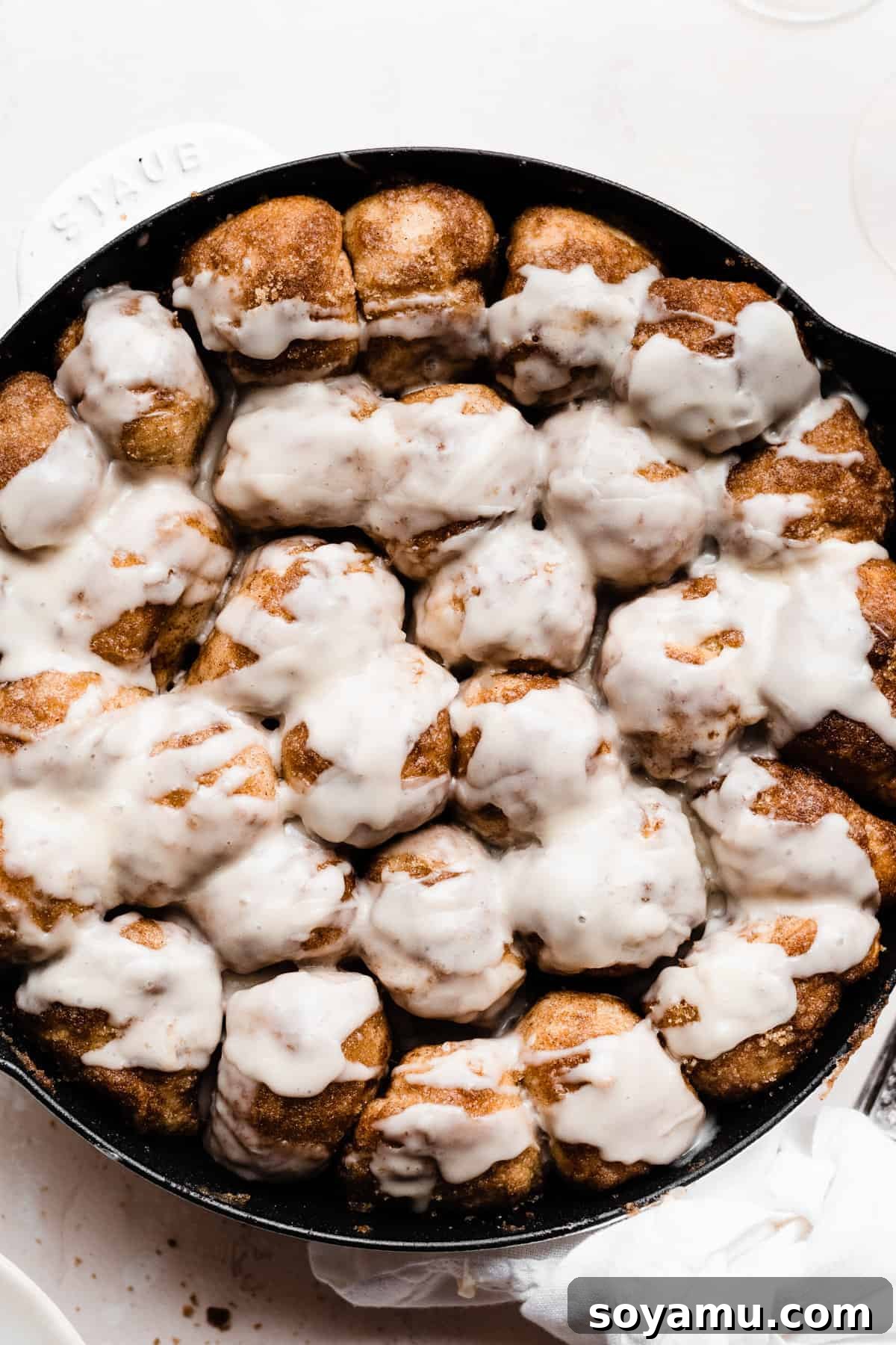 Gooey Skillet Cinnamon Roll Goodness 5 A beautifully baked skillet of cinnamon-sugared dough pieces, fresh from the oven, drizzled with a generous amount of sweet, white glaze.