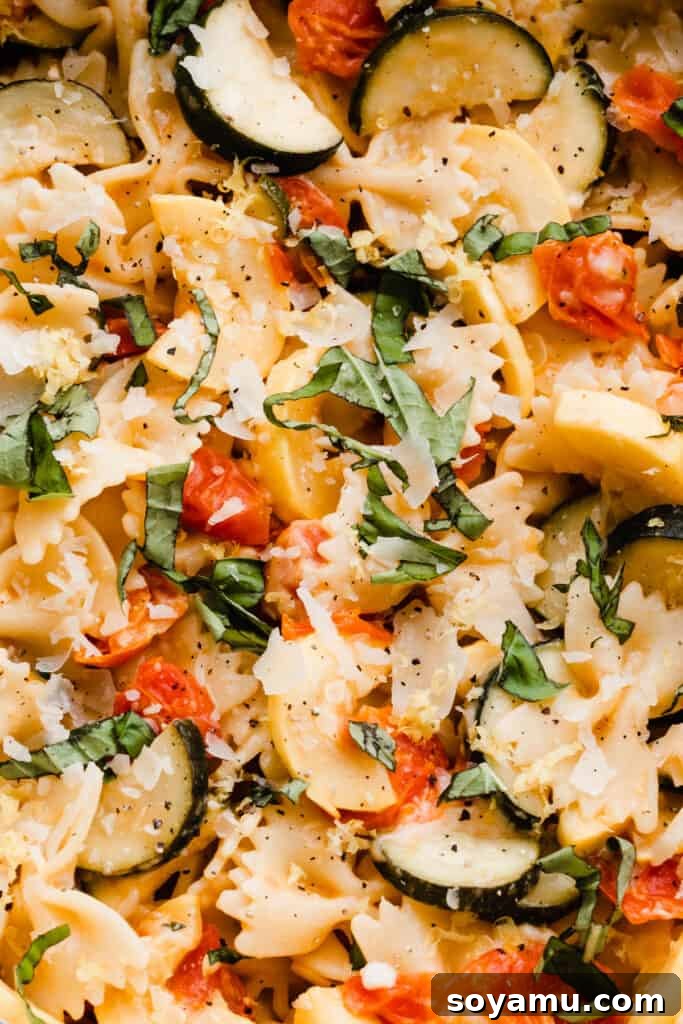 A beautiful close-up of the finished lemon butter pasta with zucchini, tomatoes, and fresh basil, showcasing its vibrant colors.