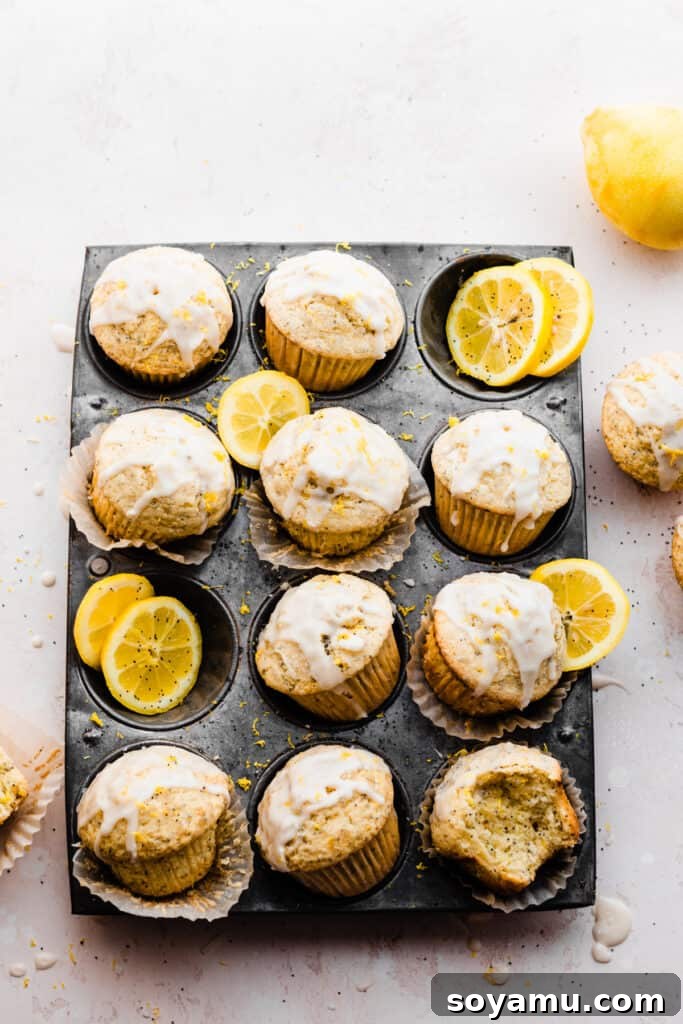 A vintage pan filled with golden-brown lemon poppyseed muffins, garnished with fresh lemon slices.