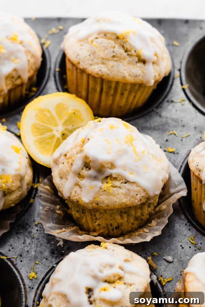 A close-up view of a glazed lemon poppyseed muffin, with a thin lemon slice carefully placed on top.